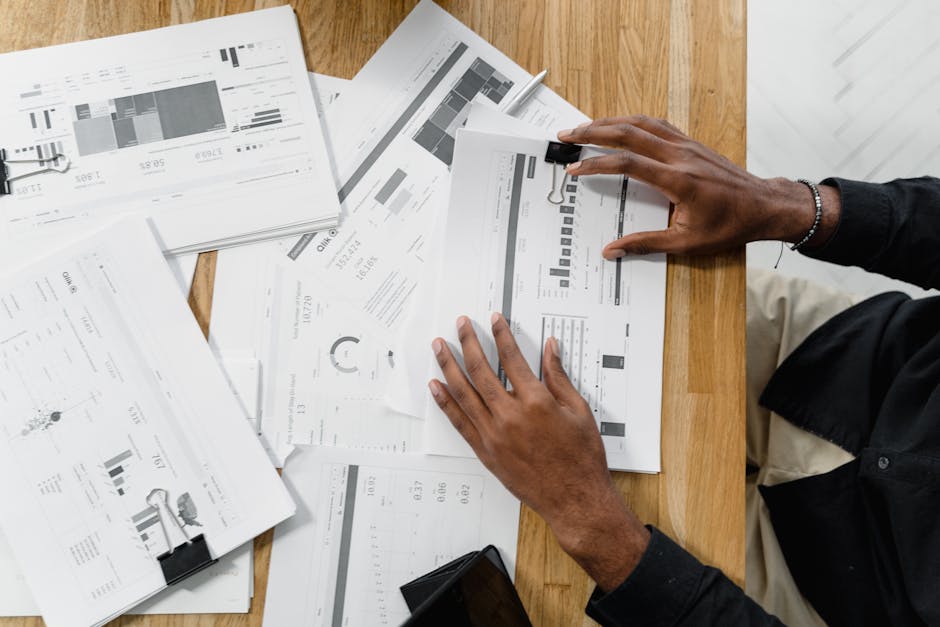 Top view of a professional reviewing financial documents at a wooden workspace.